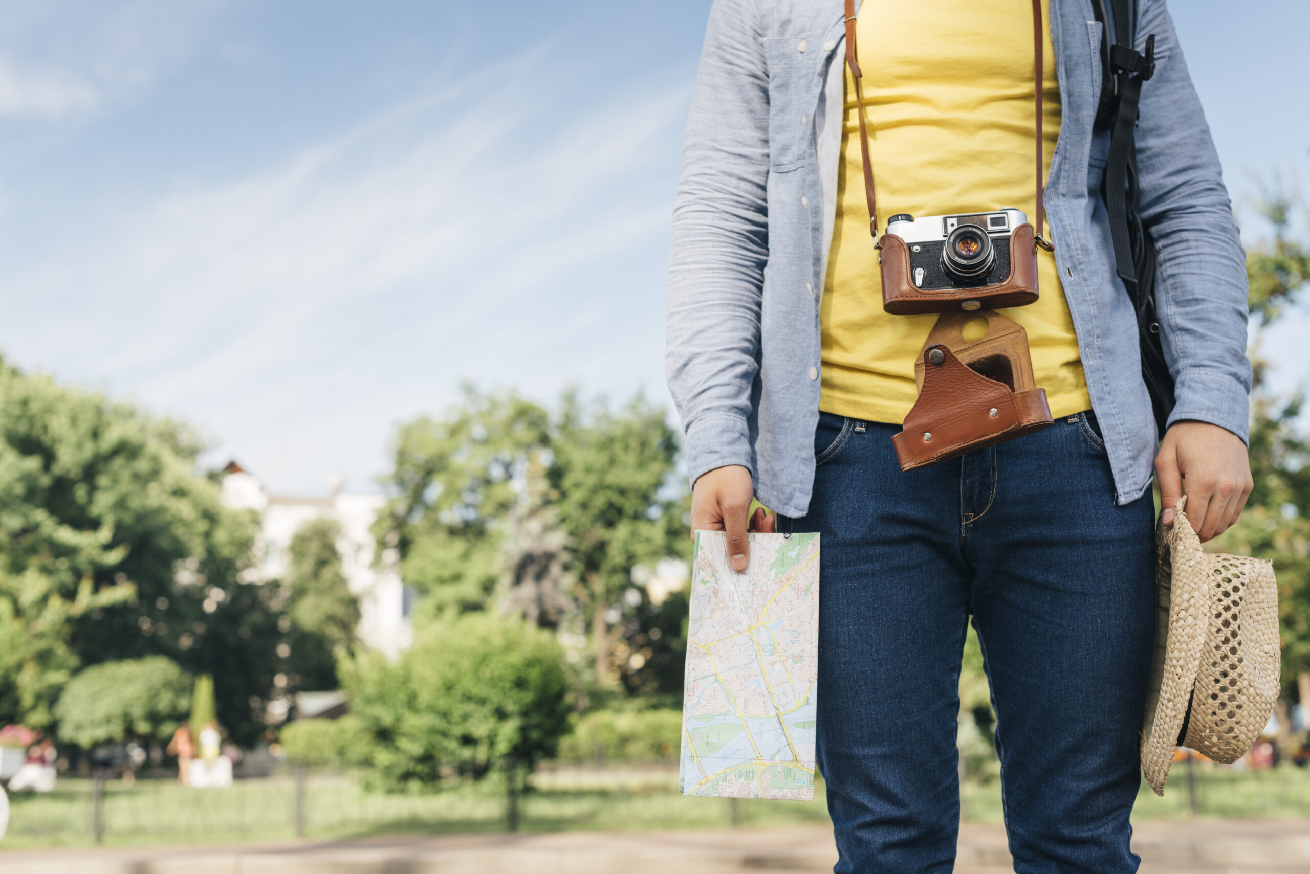 seccion-media-del-hombre-turista-que-lleva-la-camara-y-que-sostiene-el-mapa-y-el-sombrero-en-el-parque